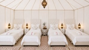 A four-bed suite with white bedding, matching nightstands, and decorative lanterns. - Remal Luxury Camp (Merzouga)