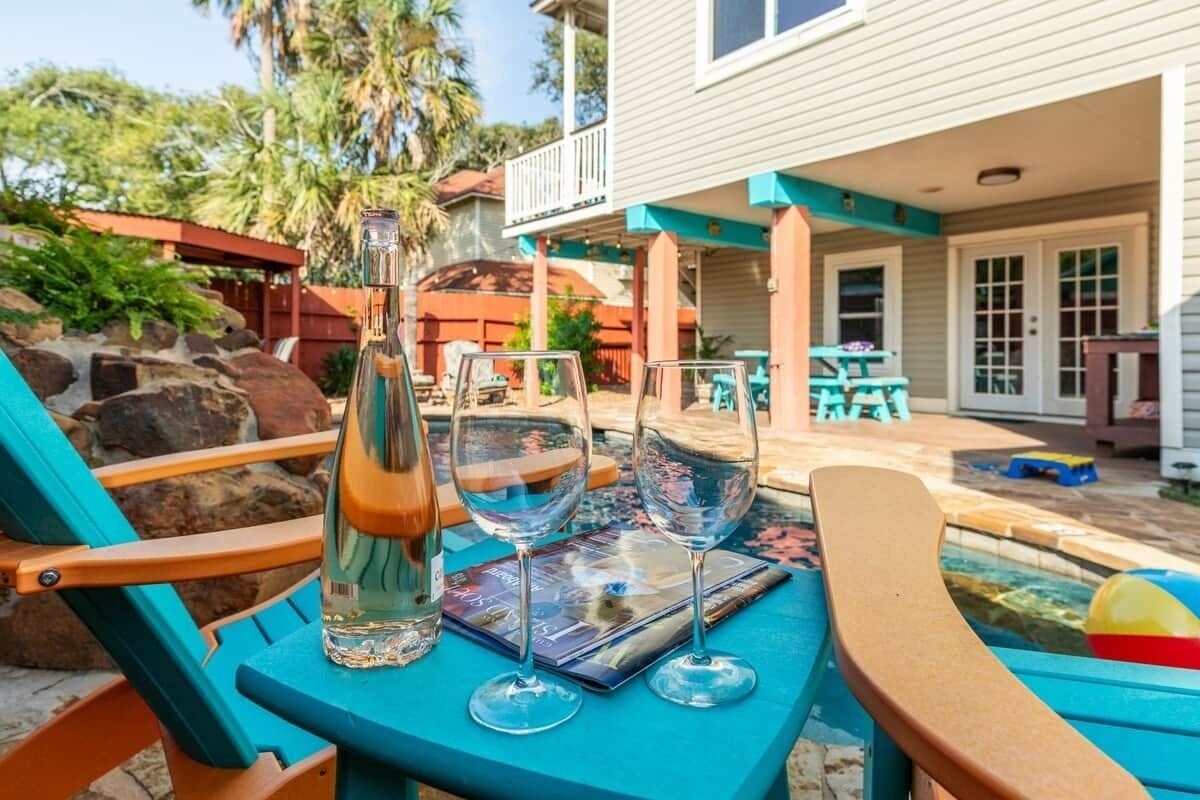 A patio with a table set for two, a bottle, and two wine glasses.