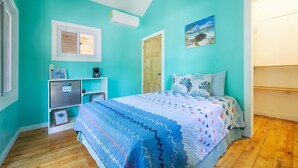 A bedroom with a bed, a desk, a chair, and a window.