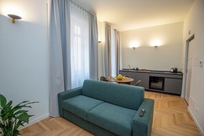 A living room with a sofa, a dining table with chairs, a kitchen area, and a potted plant. - Luxury Boutique Apartment 4 in Palermo City Center, near the Central Station (Palermo)