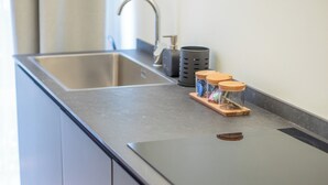 Una cocina moderna con un lavamanos de acero inoxidable, horno empotrado y encimera de madera.