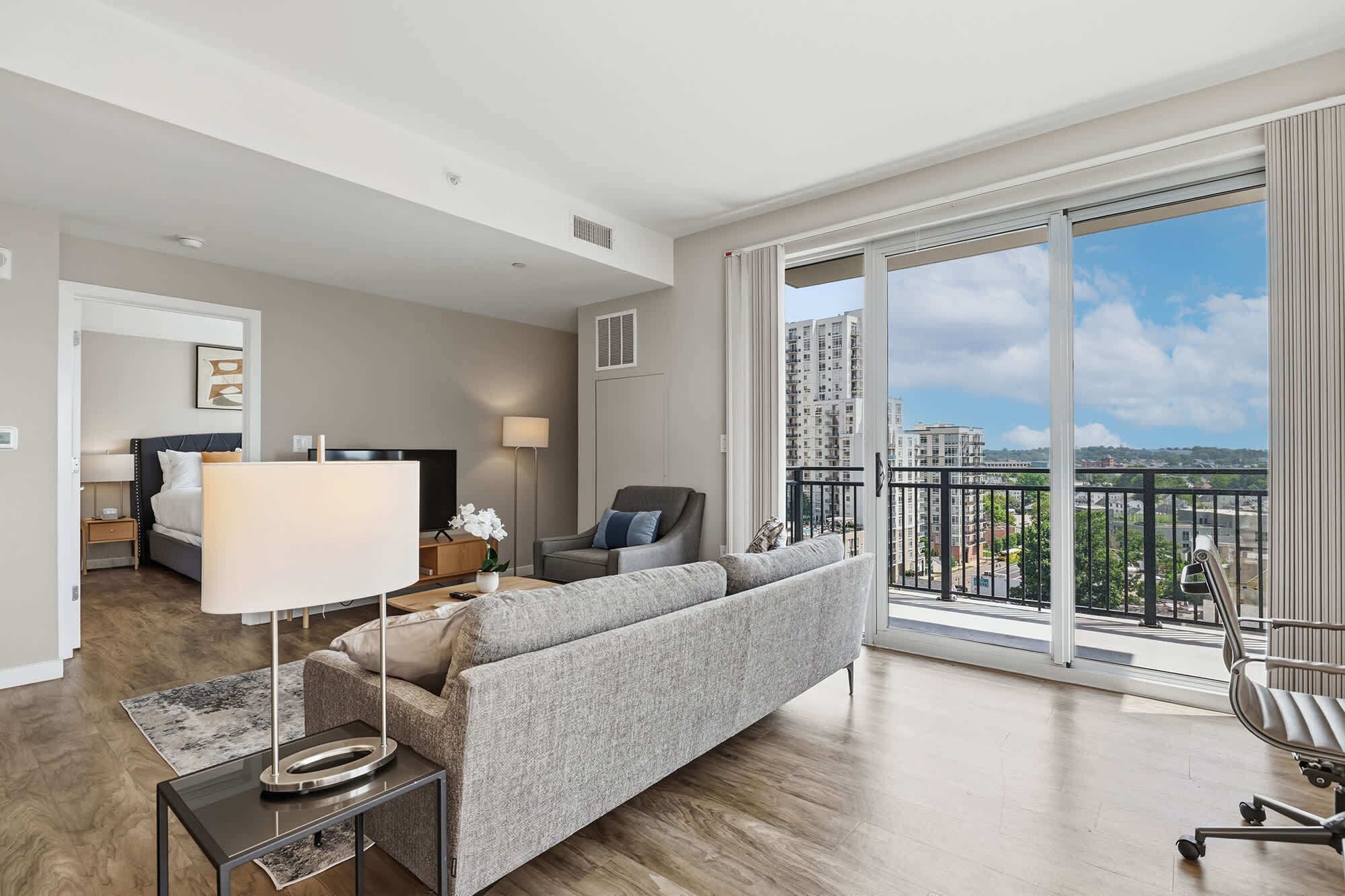 A spacious living room with a large window, a sofa, a coffee table, and a TV.