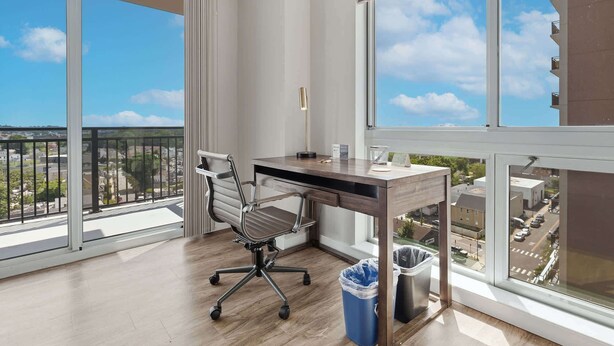 Ein moderner Arbeitsraum mit Schreibtisch, Stuhl und großen Fenstern mit Blick auf die Stadt.