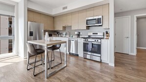 A modern kitchen with a central island, stainless steel appliances, and light wood cabinetry.