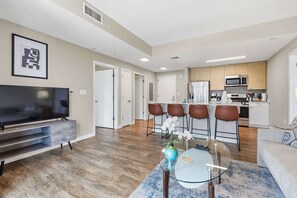 A modern living room with a flat-screen TV, a glass coffee table, and a sofa. - Luxury Harborpoint Apt (Stamford, CT)