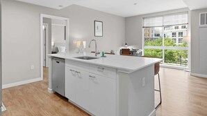 Una cocina moderna con una isla central, lavavajillas integrado y un amplio ventanal con vistas a la ciudad.