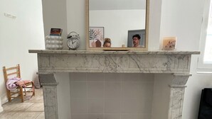 Ein Badezimmer mit Marmor-Kamin, einem Spiegel, einer Kakteen-Dekoration und einem Sessel.