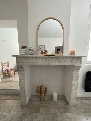 Ein Badezimmer mit Marmor-Kamin, einem Spiegel, einer Kakteen-Dekoration und einem Sessel.