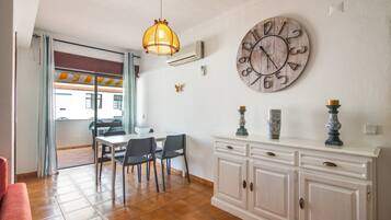 A dining area with a table and chairs, a decorative clock, and a cabinet with vases.