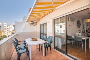 Ein Balkon mit Tisch und Stühlen, einem Korbwägelchen und Blick auf die Stadt.