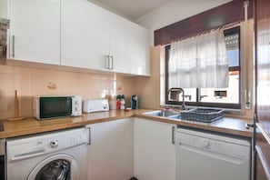 Eine kompakte Küche mit Mikrowelle, Toaster, Spüle und Geschirrspüler.