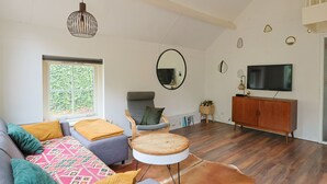 Una sala de estar con sofá, sillón, mesa redonda y televisor.