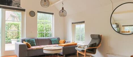A living room with a sofa, a chair, a round table, and a large mirror.