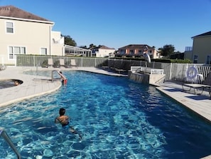 A swimming pool with a diving board, surrounded by a fence and a lifeguard chair. - Modern Townhome with Private Splash Pool, Near Disney (Clermont)