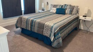 Een slaapkamer met een groot bed, nachtkastjes en een raam met gordijnen.