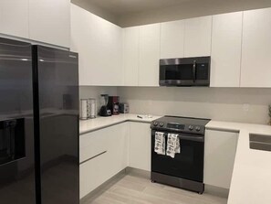 A modern kitchen with a stainless steel refrigerator, a microwave, and an oven. - Modern Townhome with Private Splash Pool, Near Disney (Clermont)