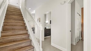 A staircase with wooden steps and white railings, leading to a room with a white door and a tiled floor. - Screened Private Pool Home, 3BR, Steps from Hidden Forest Fun (Clermont)