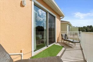 A balcony with a sliding glass door, a small grassy area, and a white fence. - Screened Private Pool Home, 3BR, Steps from Hidden Forest Fun (Clermont)