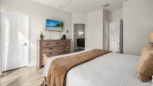 A bedroom with a bed, a dresser, a television, and a door. - Screened Private Pool Home, 3BR, Steps from Hidden Forest Fun (Clermont)