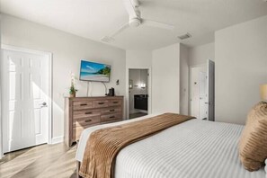 Ein Schlafzimmer mit Bett, Schminktisch, Fernseher und einer Tür.