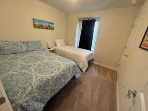 A bedroom with two beds, a window with curtains, a painting on the wall, and a carpeted floor. - Luxury 5BR Townhome with Private Pool at Windsor Cay Resort (Clermont, FL, USA)
