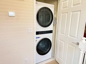 A front-loading LG washer and dryer unit installed in a hallway with a white door and light-colored walls. - TR17430PA - Affordable Disney - Townhome 3Bd 3Ba Sleeps 6 Pond view (Clermont)