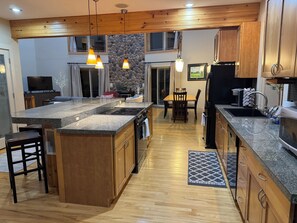 A modern kitchen with granite countertops, wooden cabinets, and a central island. - 4 Bedroom Sand Valley Golf Escape (Nekoosa)