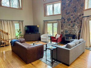 A spacious living room with a stone fireplace, a television, and a cozy seating area. - 4 Bedroom Sand Valley Golf Escape (Nekoosa)