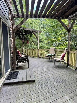 Une terrasse extérieure couverte, aménagée avec des meubles en bois et dotée d’un mur en pierre.