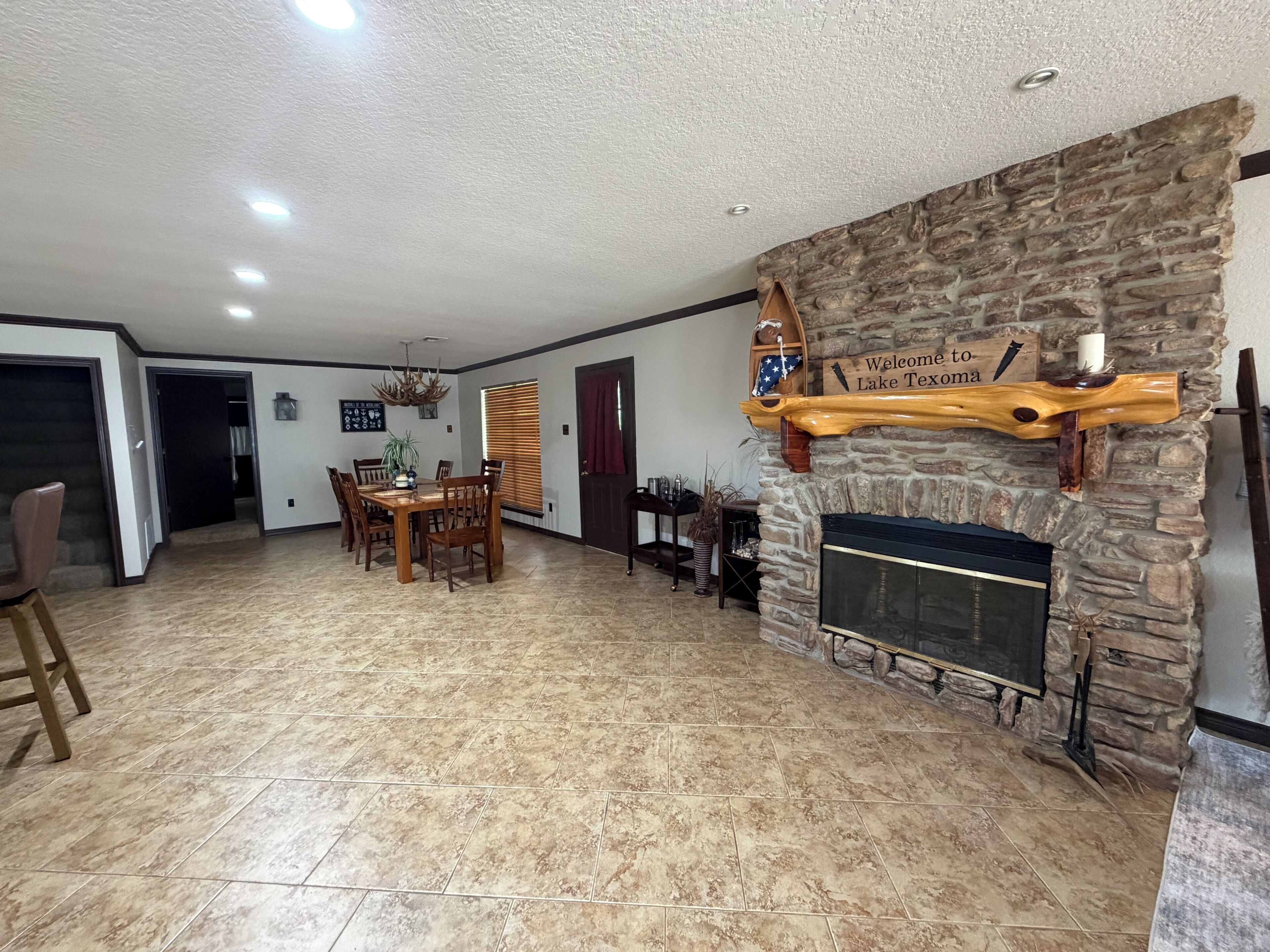 A spacious living area with a stone fireplace, a dining table with chairs, and a hallway leading to other rooms.