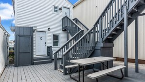 Una terraza de madera con una mesa de picnic y una escalera que lleva a un edificio.