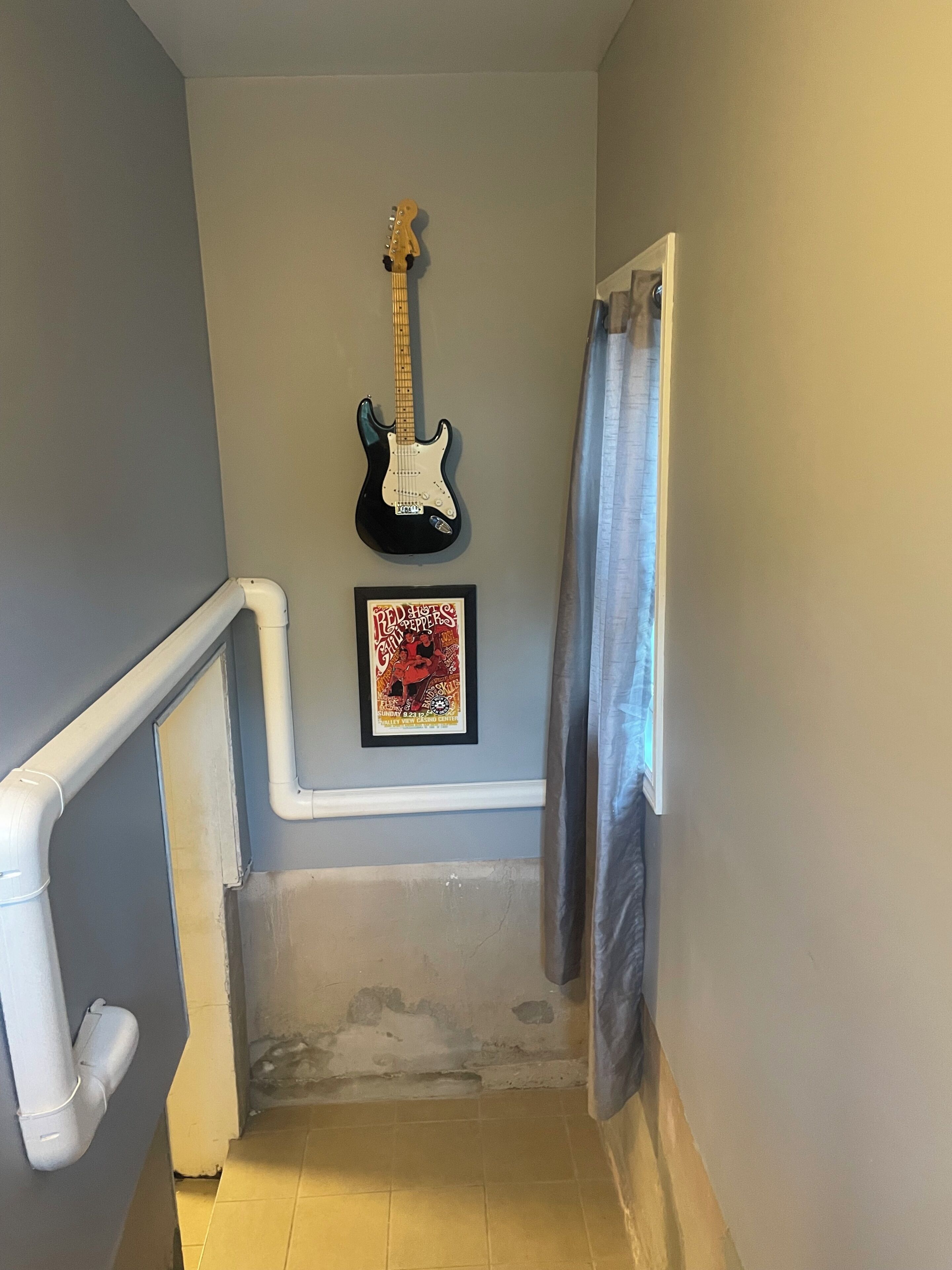 Un escalier avec une guitare et une affiche encadrée accrochée au mur.