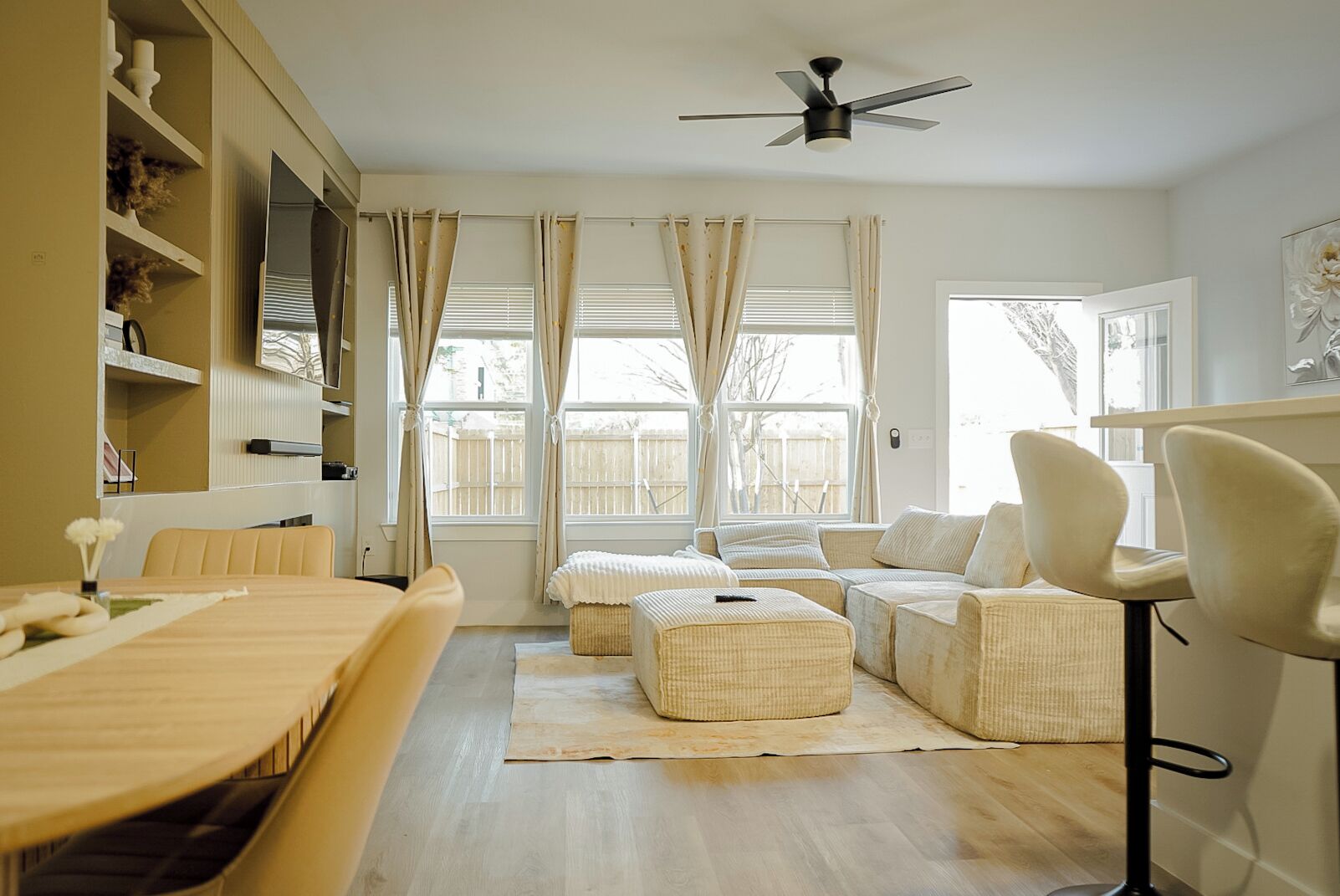 A modern living room with a sofa, ottoman, and a dining table.