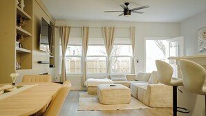 Una sala moderna con un sofá, un reposapiés y una mesa de comedor.