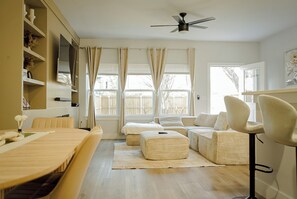 A modern living room with a sofa, ottoman, and a dining table. - Modern 3BR Near Downtown Dallas. Sleeps 6 (Dallas)