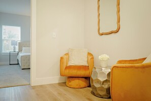 A modern living room with a sofa, a chair, a side table with a vase, and a mirror on the wall. - Modern 3BR Near Downtown Dallas. Sleeps 6 (Dallas)