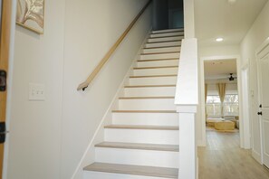 A staircase with wooden steps and a handrail, leading to a room with a bed and a window. - Modern 3BR Near Downtown Dallas. Sleeps 6 (Dallas)
