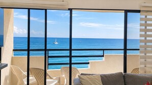 Varanda com vista para o mar, um ventilador de teto e um sofá com almofada.