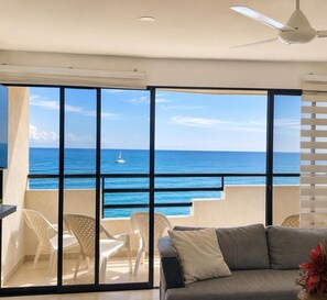 Ein Balkon mit Blick auf das Meer, ein Deckenventilator und ein Sofa mit Kissen.