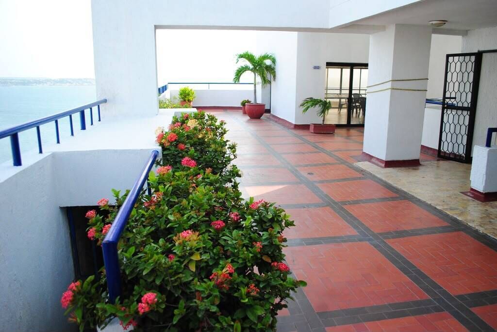 A hotel corridor with a railing, potted plants, and a view of the sea.