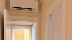 Un pasillo con un equipo de aire acondicionado instalado en la pared, suelo de madera y puertas blancas.