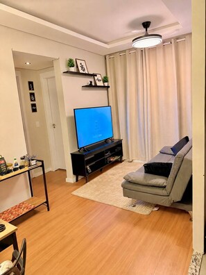 A living room with a flat-screen TV, a sofa, a coffee table, and a small dining area. - NEW Apartment | Incredible Comfort | Rodeo Festival | Near Hospital de Amor (Barretos)