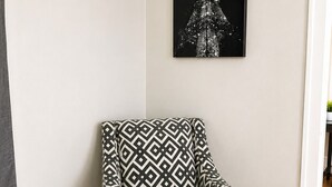 A corner room with a patterned armchair, a framed picture on the wall, and a wooden floor. - Modern Downtown Studio - Walk to Toyota Center (Houston)