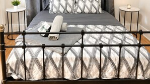 A bed with a metal frame, grey curtains, and patterned bedding. - Modern Downtown Studio - Walk to Toyota Center (Houston)