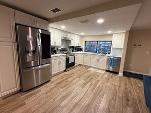 A kitchen with white cabinets, stainless steel appliances, and a window with a view.