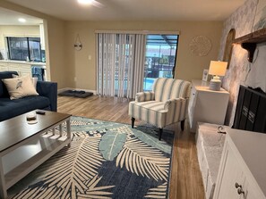 A living room with a sofa, armchair, coffee table, and a patterned rug.