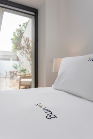 Ein Hotelzimmer mit Bett, Fenster und Blick auf einen Außenbereich mit Tisch und Stühlen.