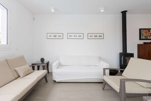 Ein Wohnzimmer mit einem weißen Sofa, einem Sessel, einem kleinen Tisch und einem Kamin.