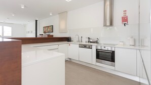 Een moderne keuken met witte kastjes, een roestvrijstalen afzuigkap en een Bosch vaatwasser.
