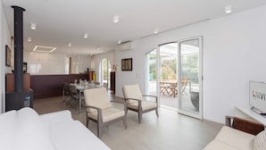 Een moderne woonkamer met een bank, stoelen, een eethoek en een keuken op de achtergrond.